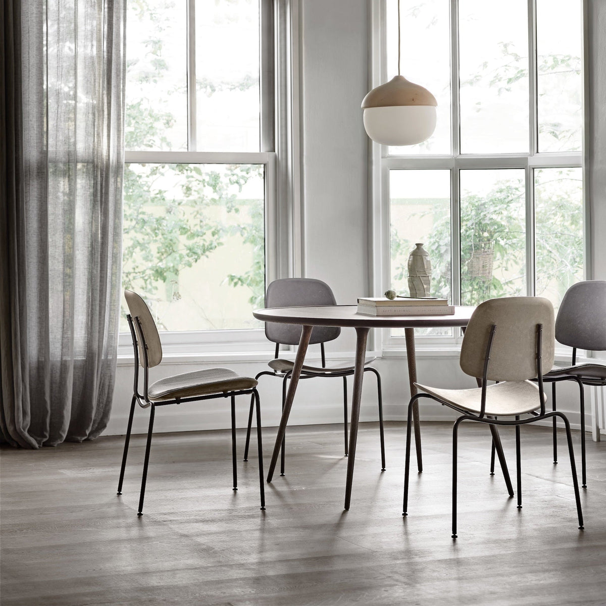 Mater Compound dining chairs around a round oak Mater table by tall windows