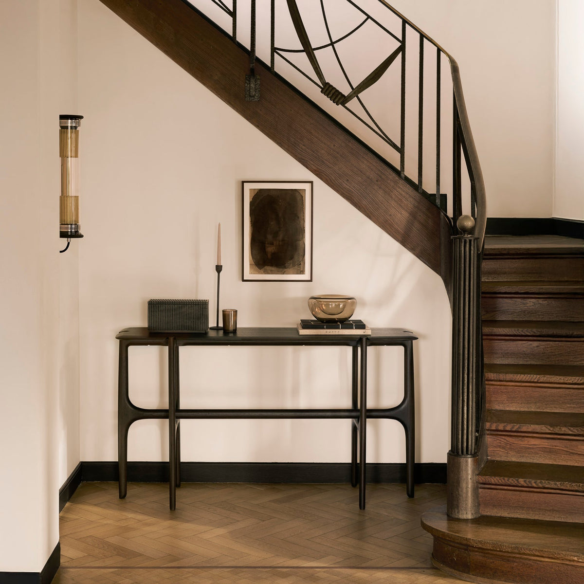 Ethnicraft PI console table in dark-brown varnished teak styled in an entryway beneath a wooden staircase