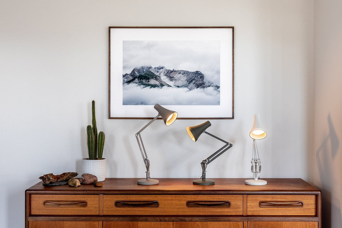 Anglepoise task lamps on a walnut sideboard beneath a framed landscape photograph