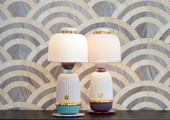 Two porcelain table lamps with pleated shades on a patterned marquetry surface