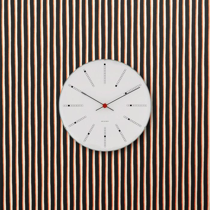 A white Arne Jacobsen wall clock mounted on a slatted oak wall
