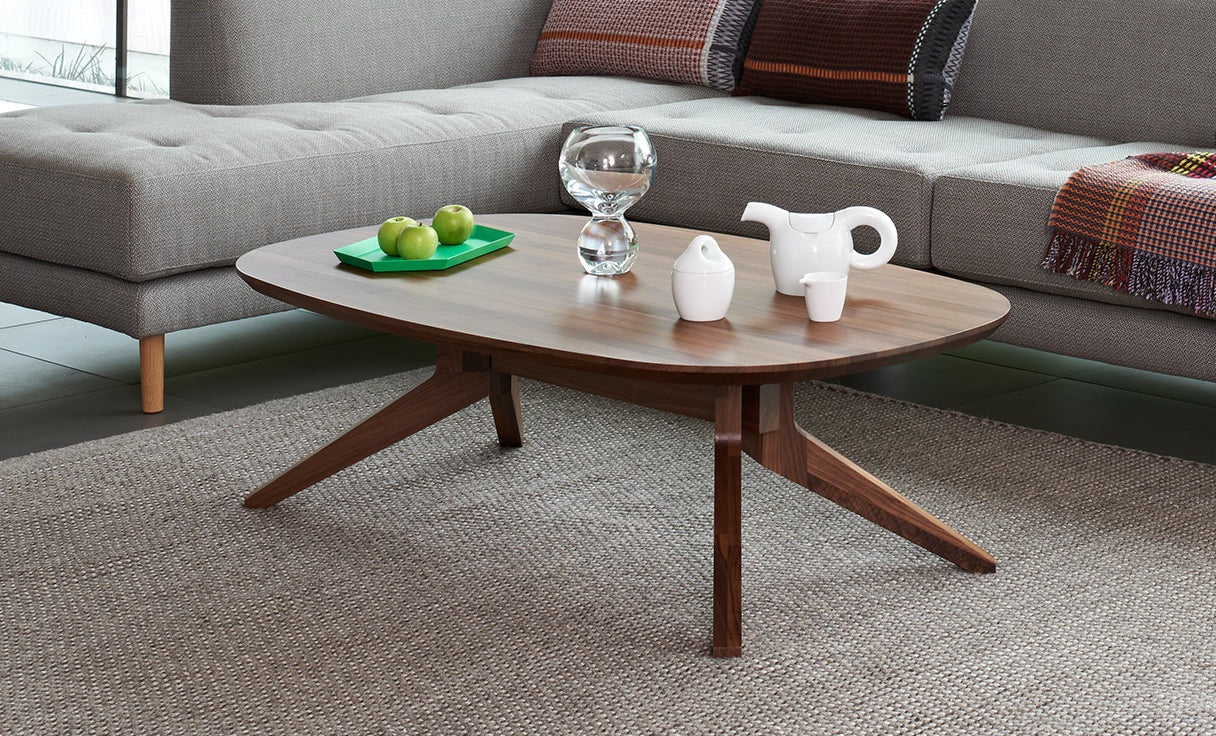 A grey sofa with a walnut coffee table styled with glassware and a small bowl of fruit