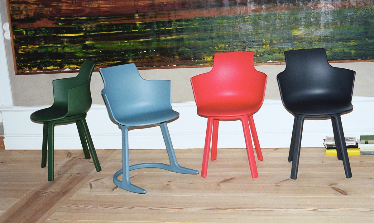 Green, blue, red and navy ergonomic chairs lined up in front of a painted mural