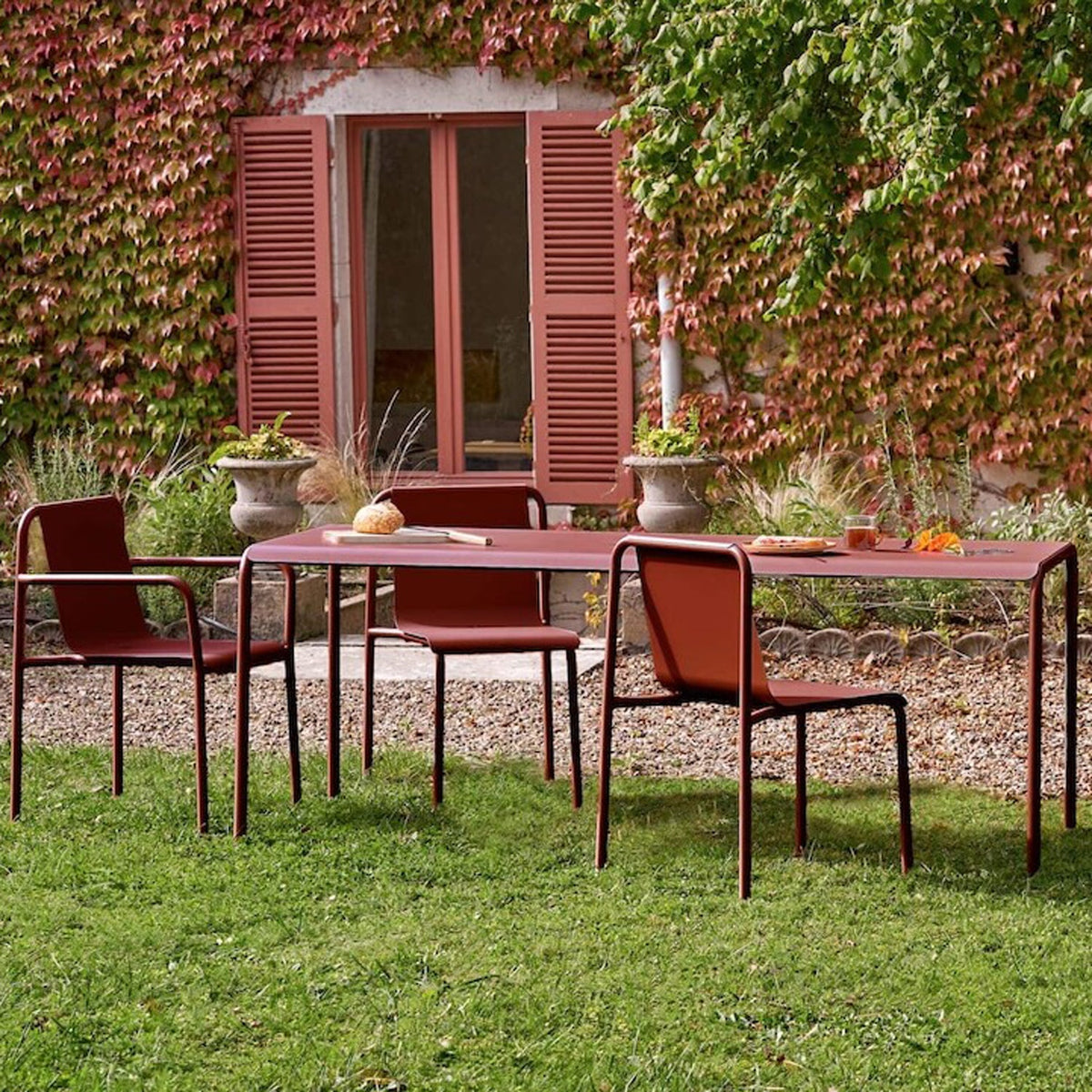 Tiptoe PANORAMA Outdoor Chairs in Brick Red around a garden table, powder-coated steel
