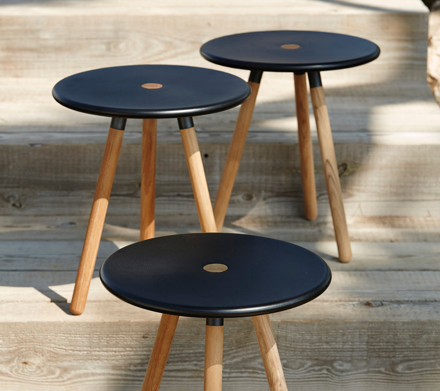 Three black stools with wooden legs on a wooden floor