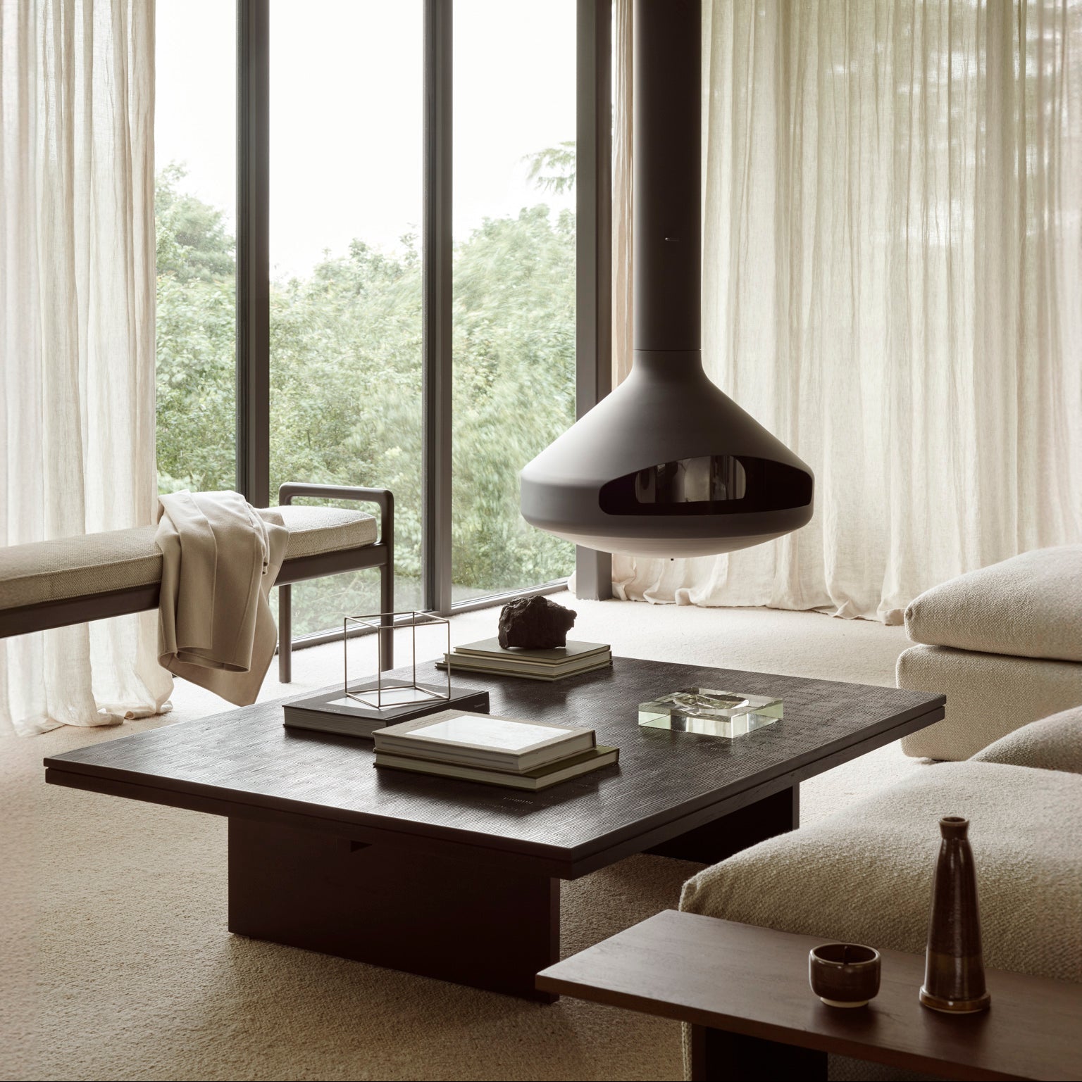 Modern living room with a hanging fireplace, large windows, and minimal decor.