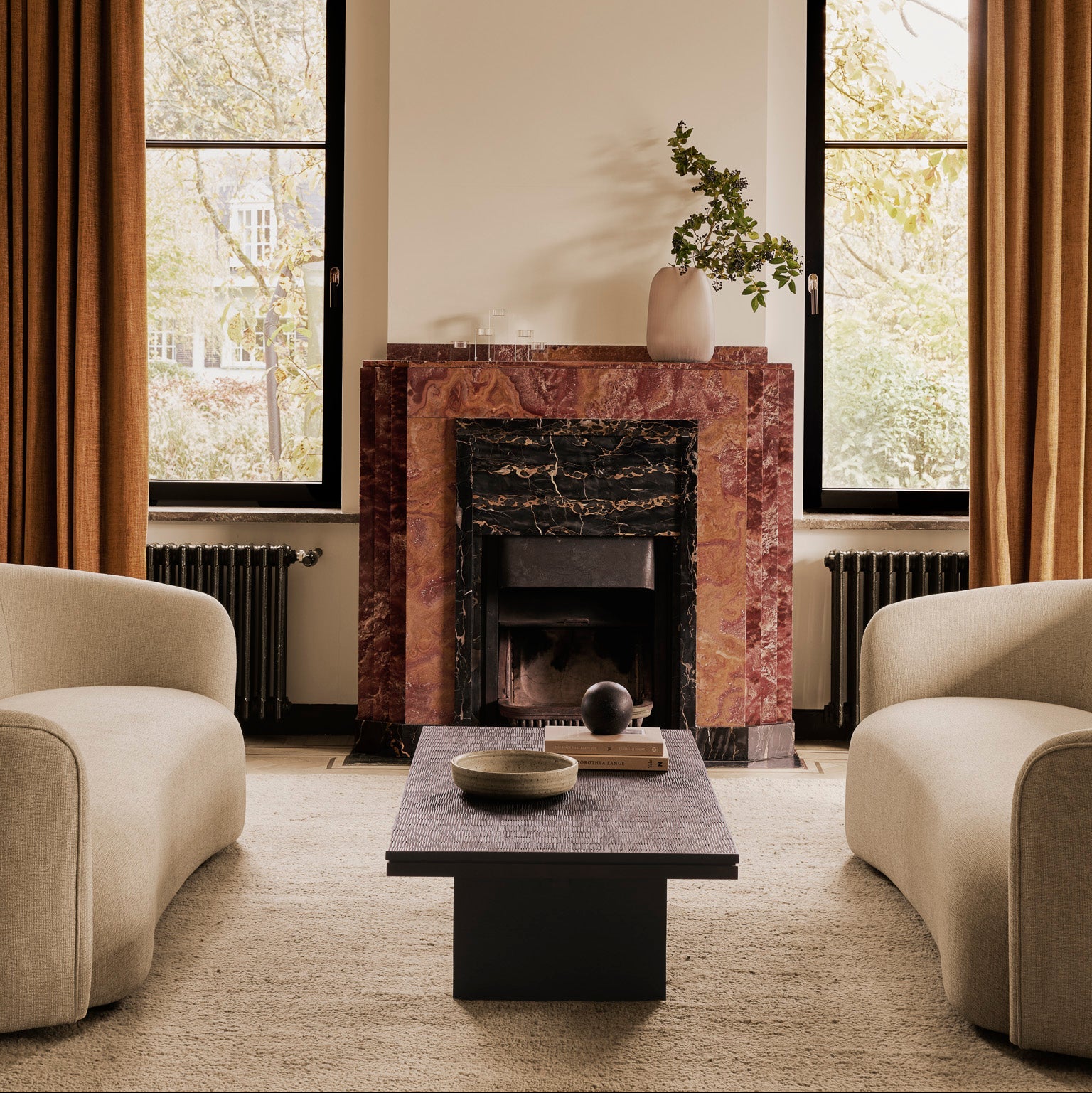 Modern living room with a fireplace, two beige armchairs, and a coffee table.