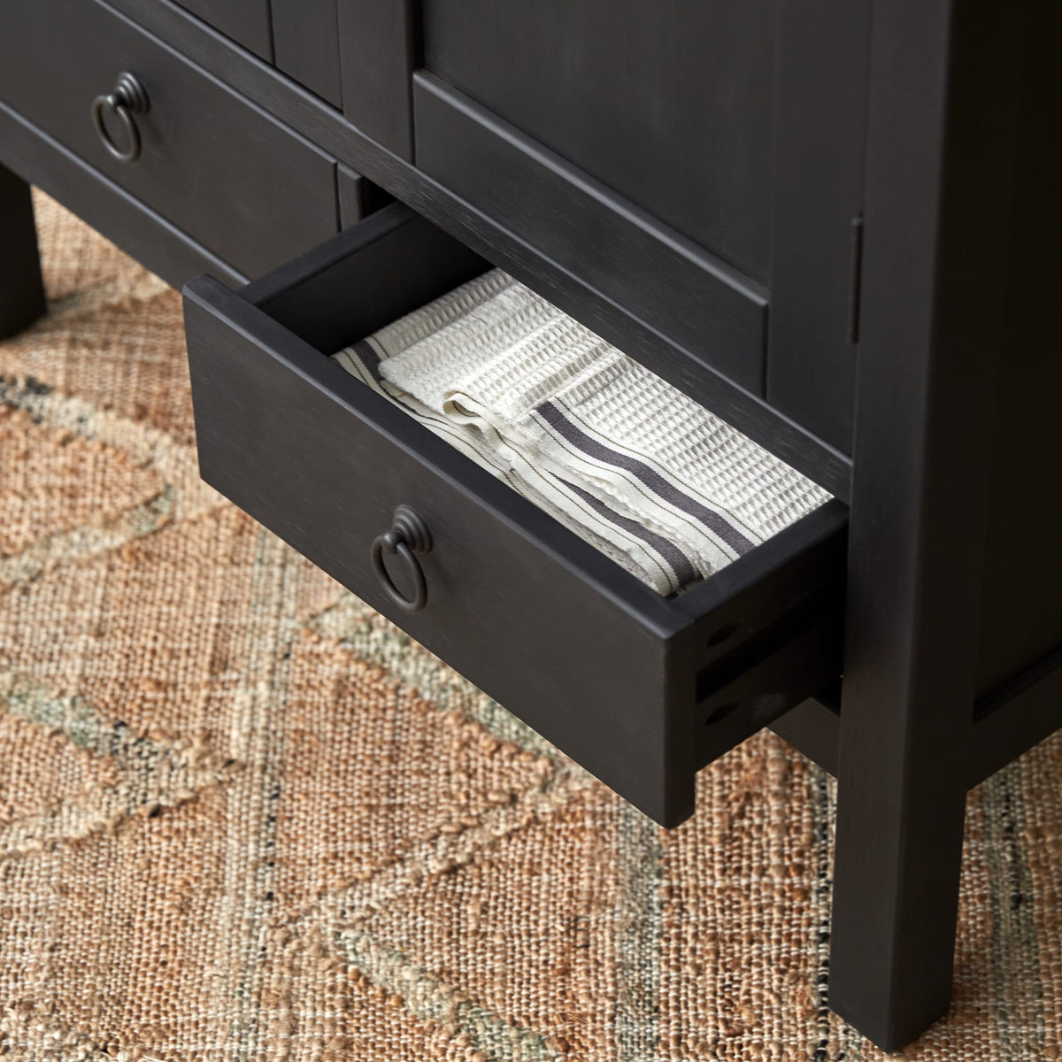 Thaki Black cabinet drawer pulled open with folded linens