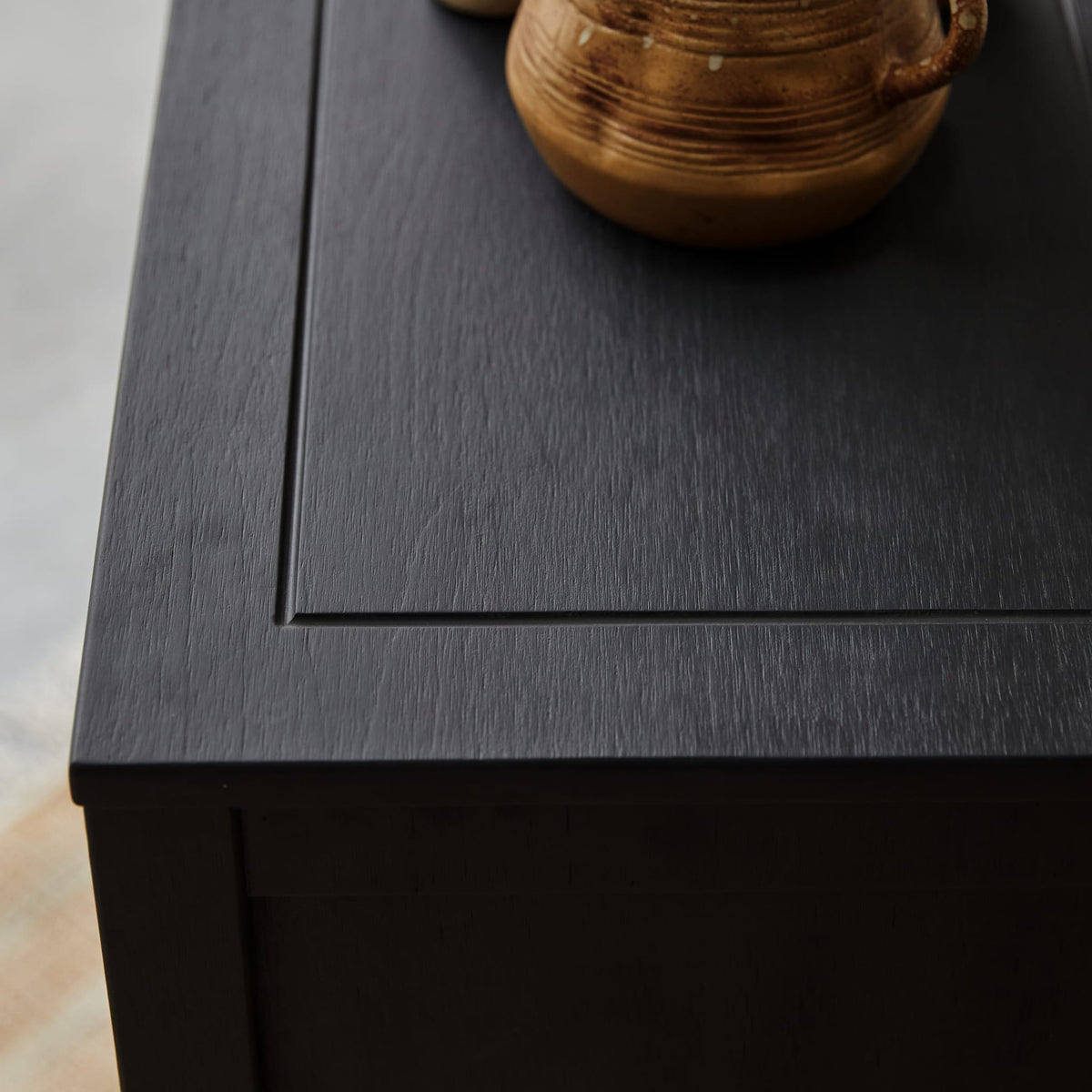 Detail of the Thaki Black cabinet top showing the painted pine grain