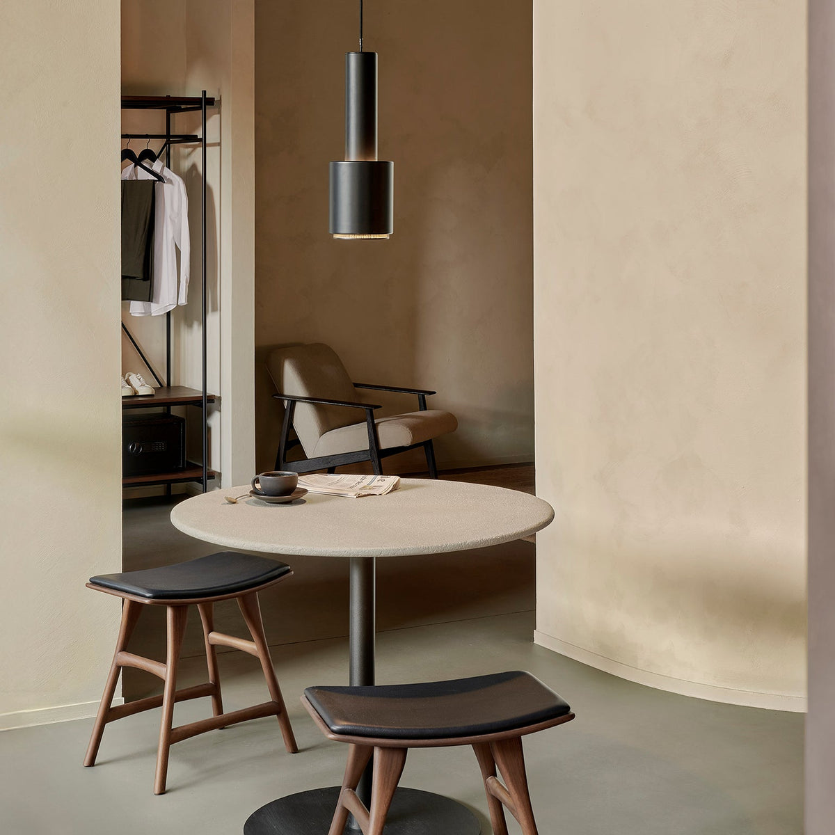 Ethnicraft Blend table in Off White Microcement, styled in a café interior, Dark Bronze metal base