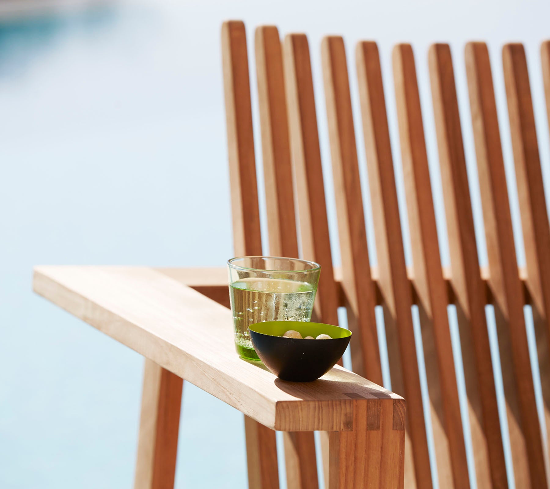 Wooden chair with a glass of water and a bowl on a blurred outdoor background
