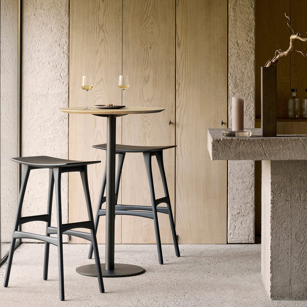 Ethnicraft Blend Bar Table in Oak with Osso bar stools, styled in an interior setting, solid oak top on metal base