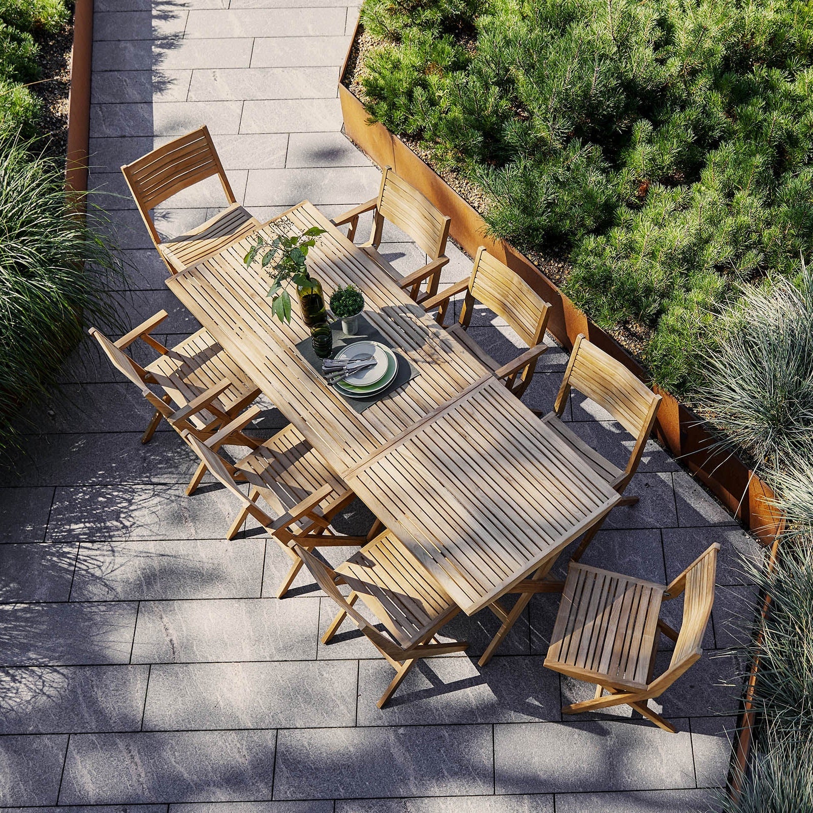Large teak dining table with folding chairs by Cane-line, sustainable outdoor furniture Comosum