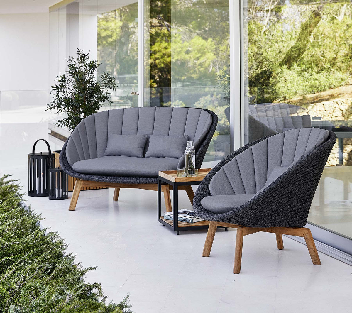 Cane-line Peacock 2-seater Sofa in Dark Grey with matching lounge chairs, styled on a terrace, Soft Rope and teak
