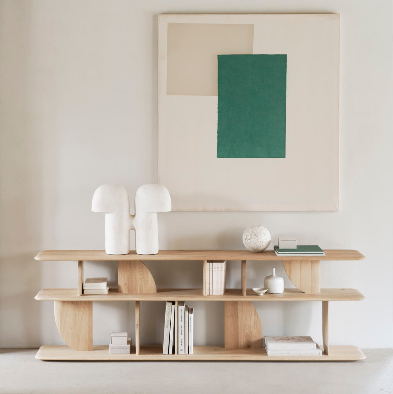 Modern interior with a wooden shelf, abstract art, and white decor items.