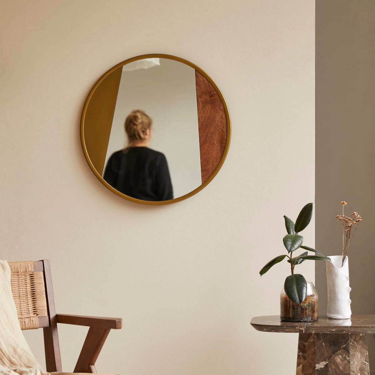 Andrea round mirror in gold metal and wood, front view on a white wall