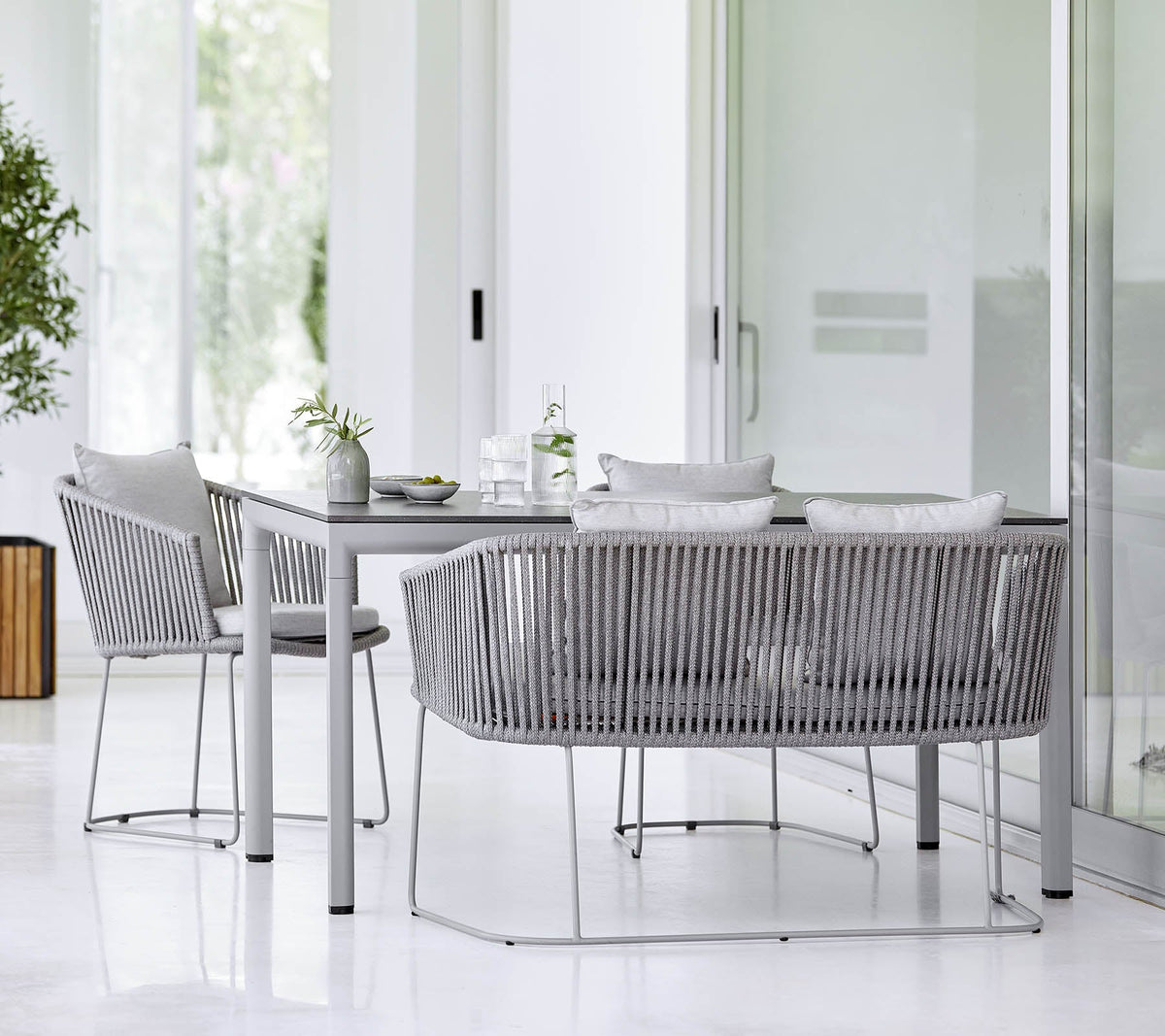 Cane-line Moments Bench in Grey with Moments dining chairs at a table, styled outdoors, Soft Rope
