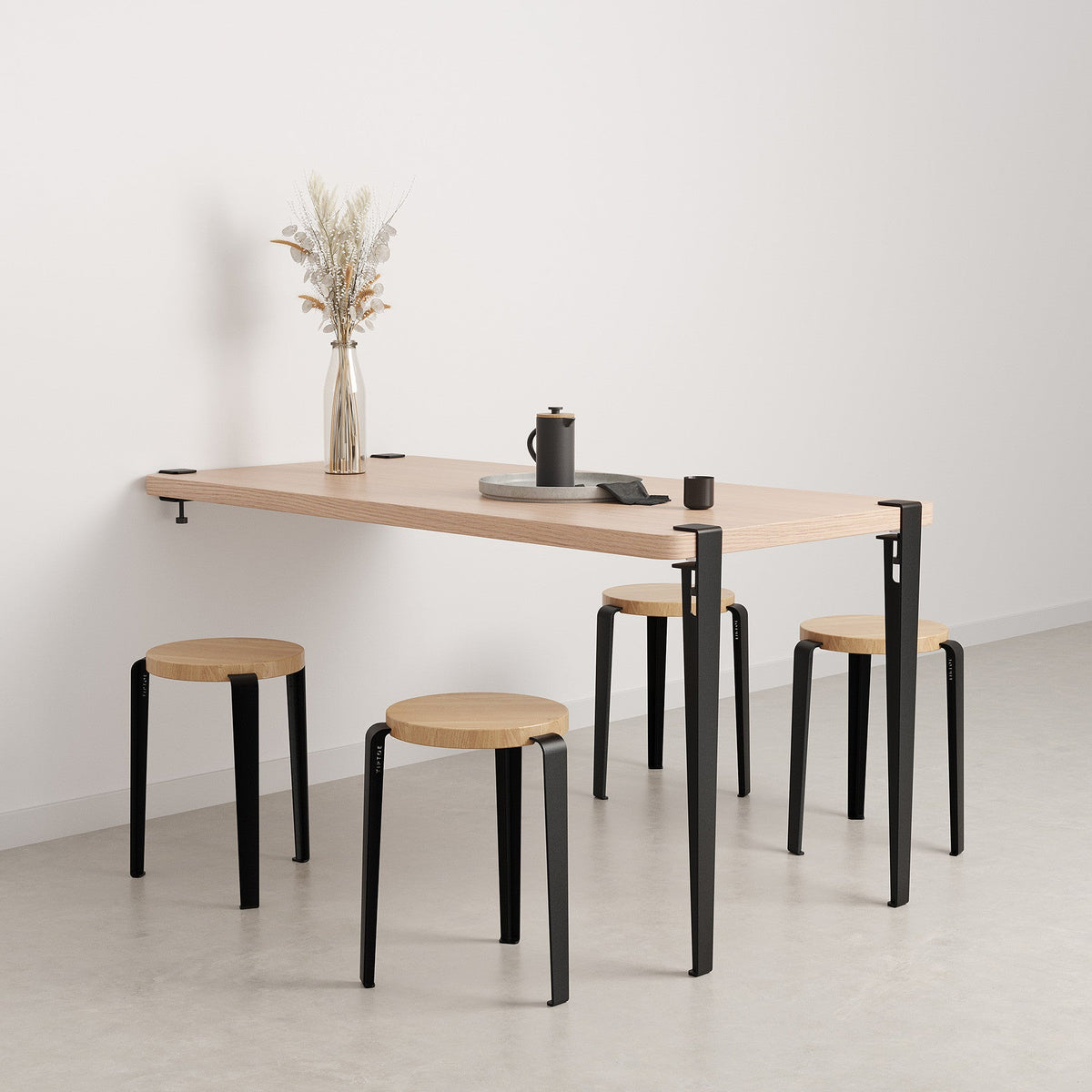 Tiptoe Wall Desk 150 x 75 cm in Graphite Black, styled with stools as a dining table, oak veneer and steel