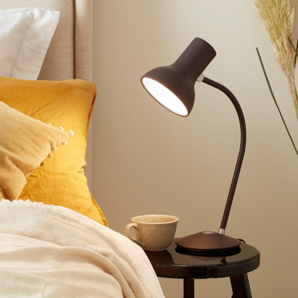 Anglepoise Type 75 Mini table lamp in Black Umber on a bedside table with a yellow throw