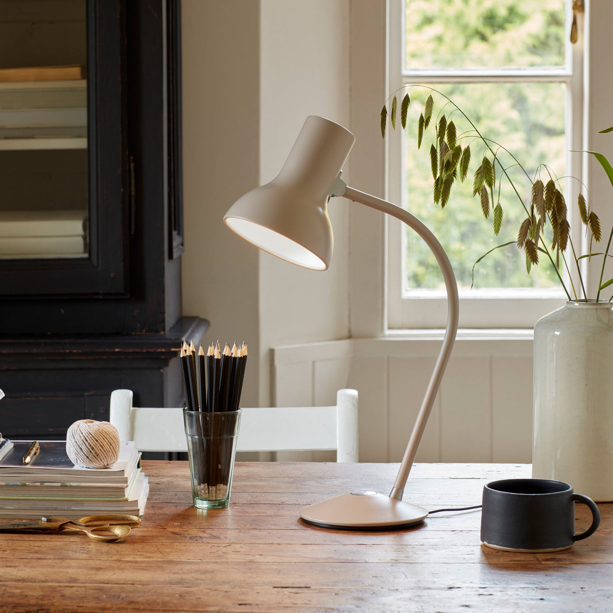 Anglepoise Type 75 Mini table lamp in Mole Gray on a wooden table by a window
