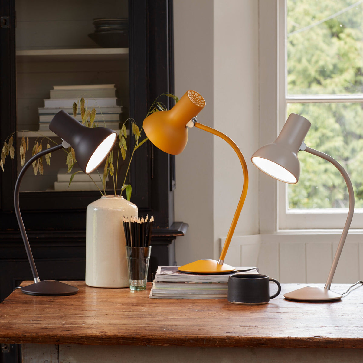 Three Anglepoise Type 75 Mini table lamps in Black Umber, Turmeric Gold and Mole Gray on a wooden table