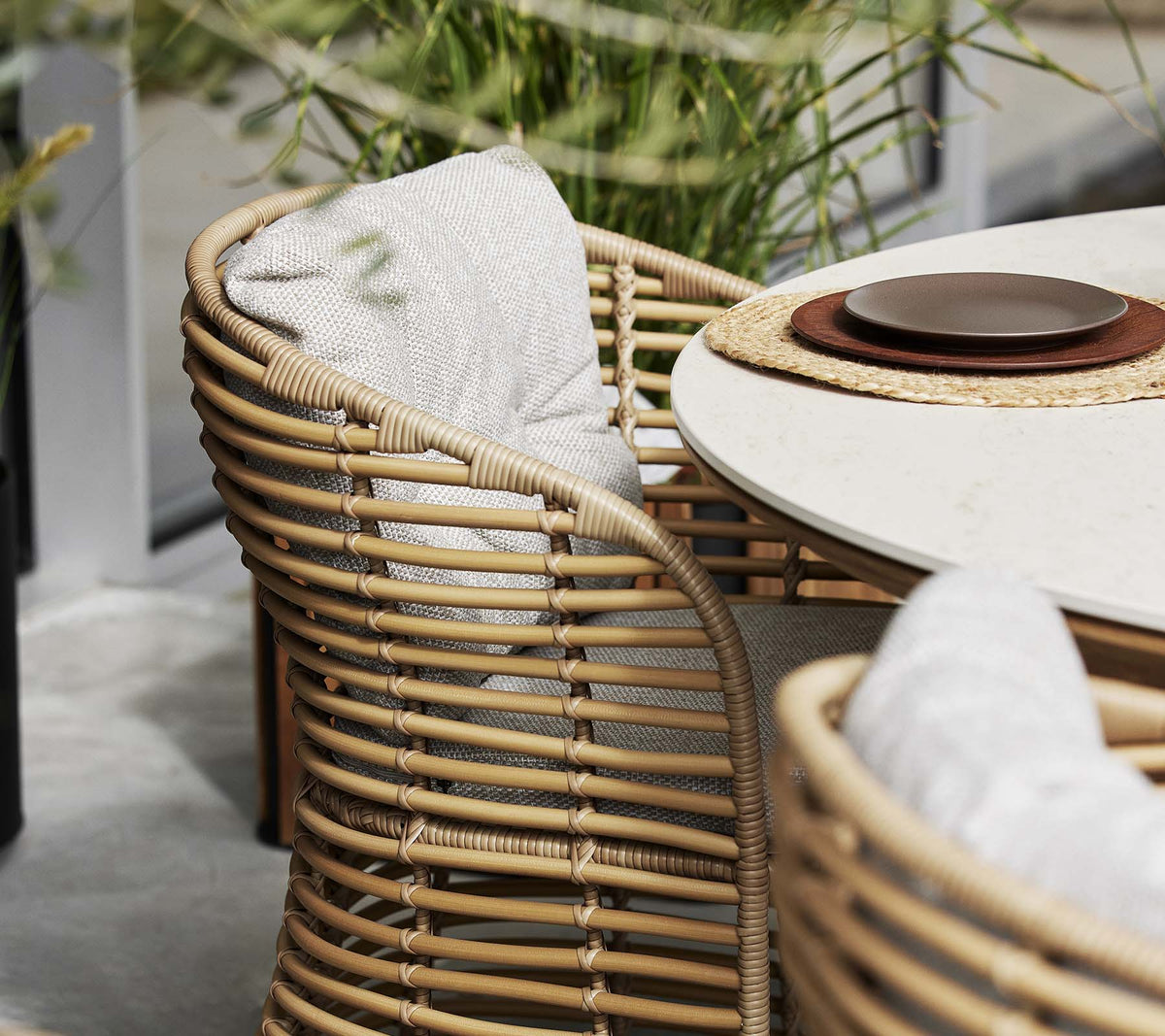 Cane-line Basket Dining Chair in hand-woven Cane-line Weave beside a laid table, styled outdoors