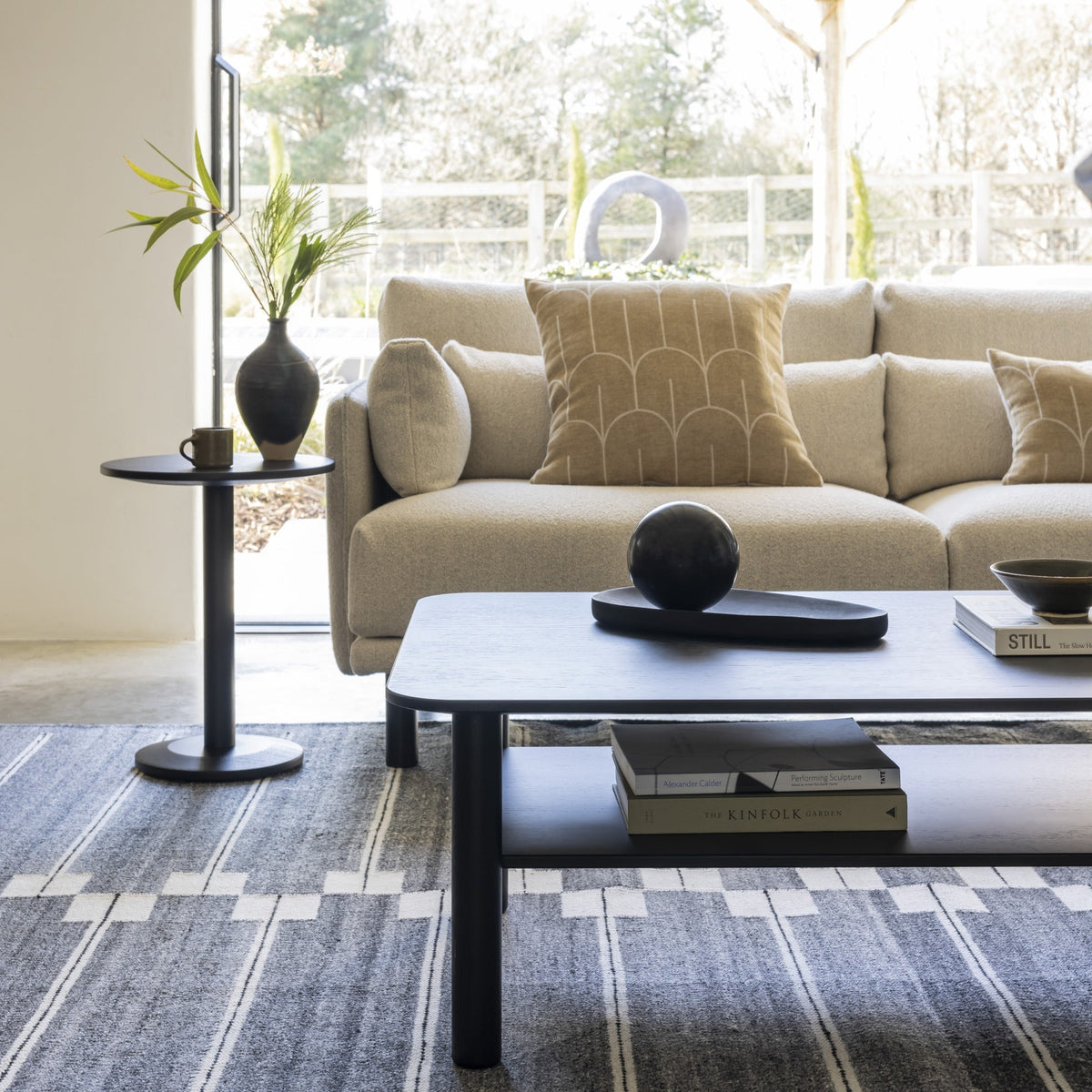 Case Spine RPET Rug in Warm Grey under a coffee table, styled in an interior setting, recycled PET flat weave