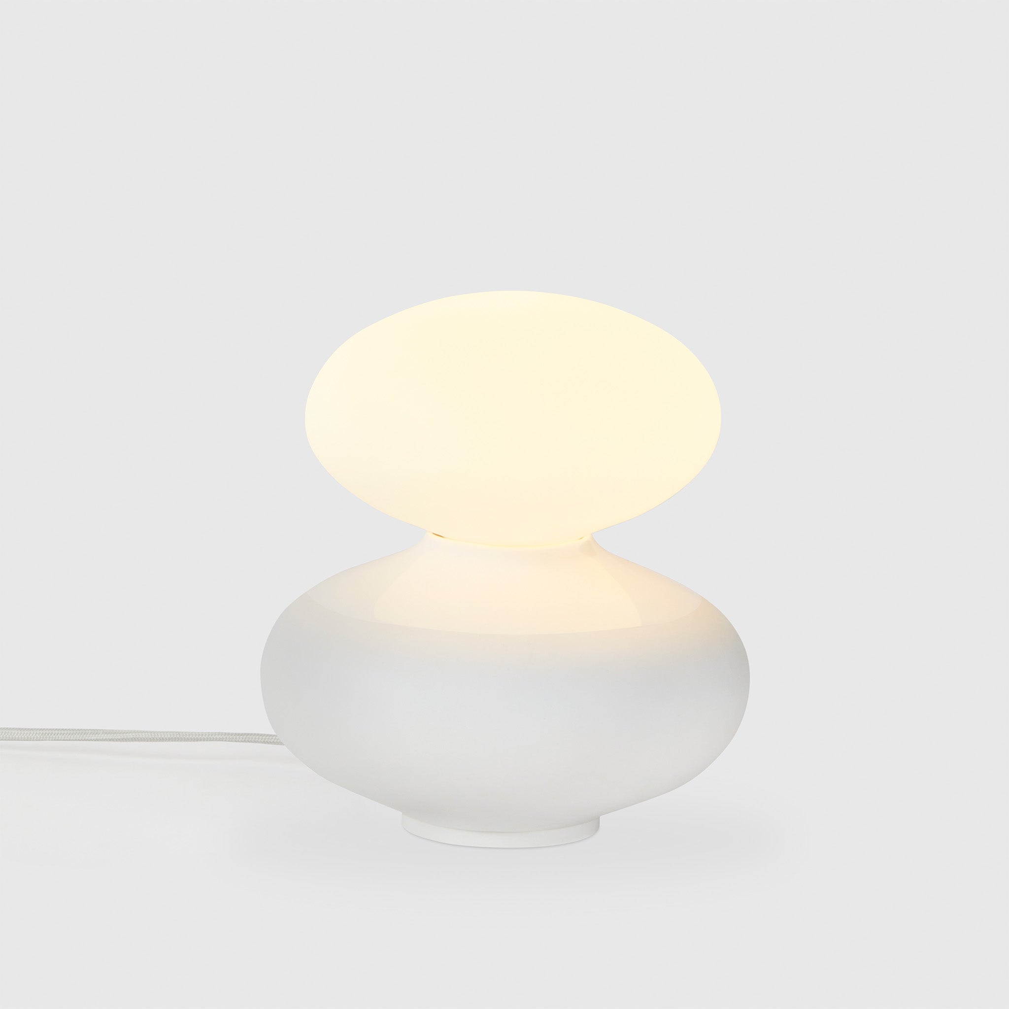 Tala Reflection Oval Table Lamp, lit, on grey background