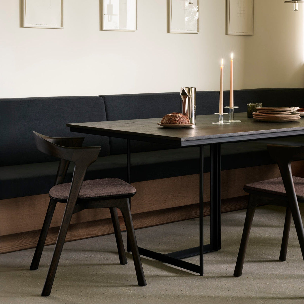 Ethnicraft Tacet Dining Table in dark brown teak set for dinner, styled in an interior setting, black metal base