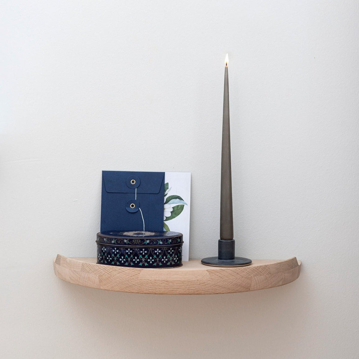 Aakjaer Arcus Console Shelf in white oiled oak holding a candlestick, a box and cards