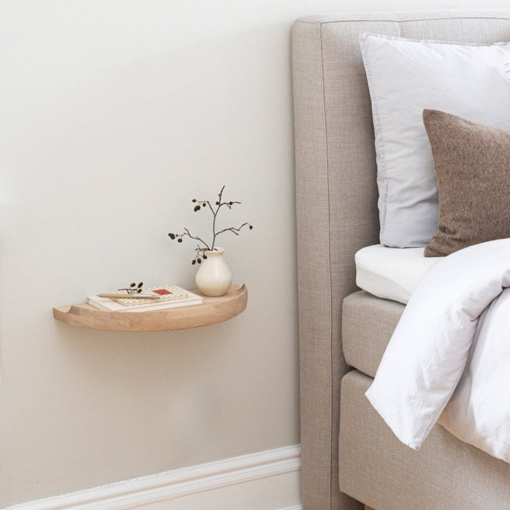 Aakjaer Arcus Console Shelf in white oiled oak mounted beside a bed as a nightstand