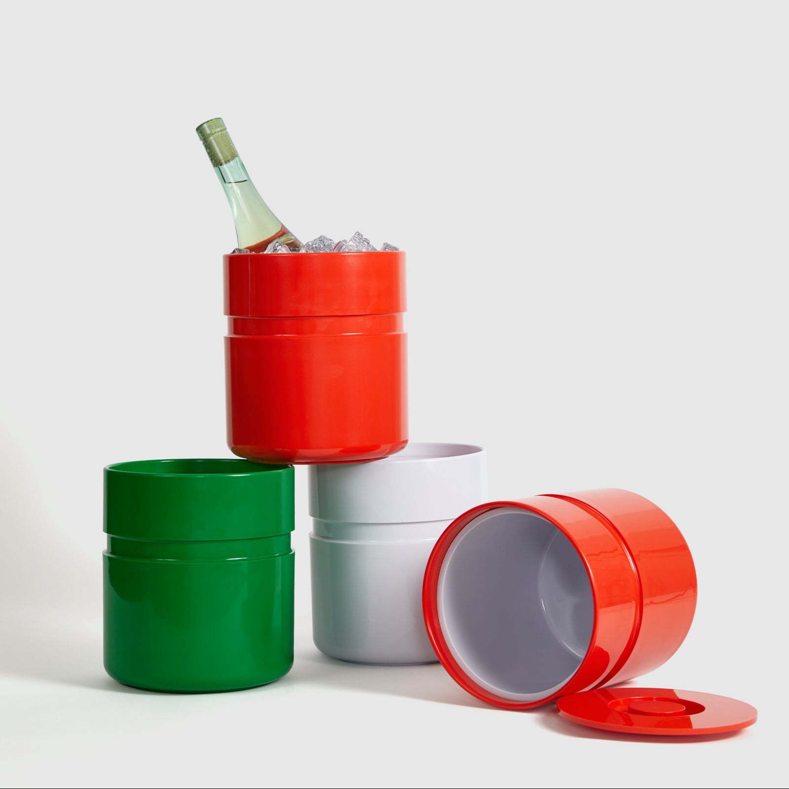 Stackable containers in red, green, and silver with a bottle of wine inside on a white background