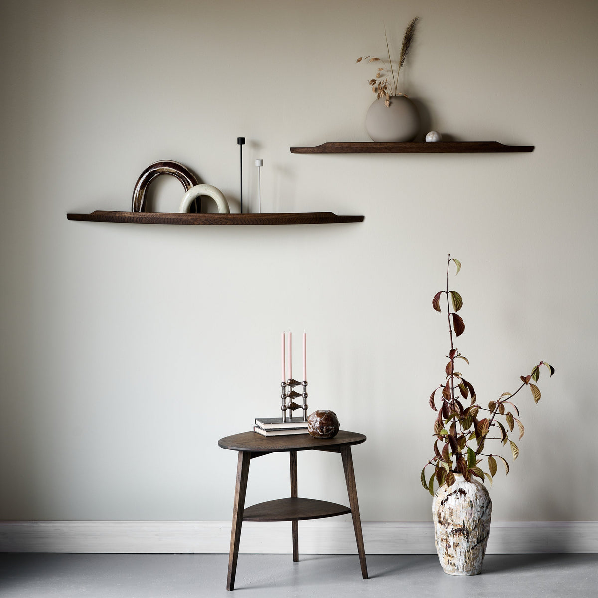 Two Aakjaer Arcus shelves in smoked oak above a small side table and dried flowers