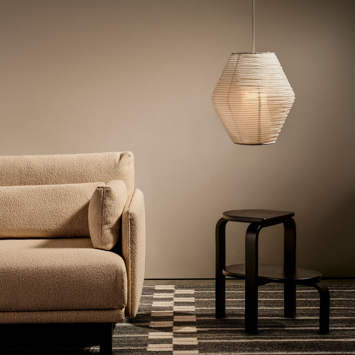Case Spine RPET Rug in Warm Grey, styled in a living room with a sofa and stool, recycled PET flat weave
