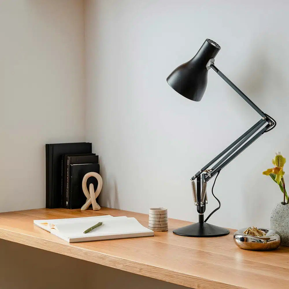 Anglepoise Type 75 desk lamp in Jet Black on an oak desk beside a stack of books