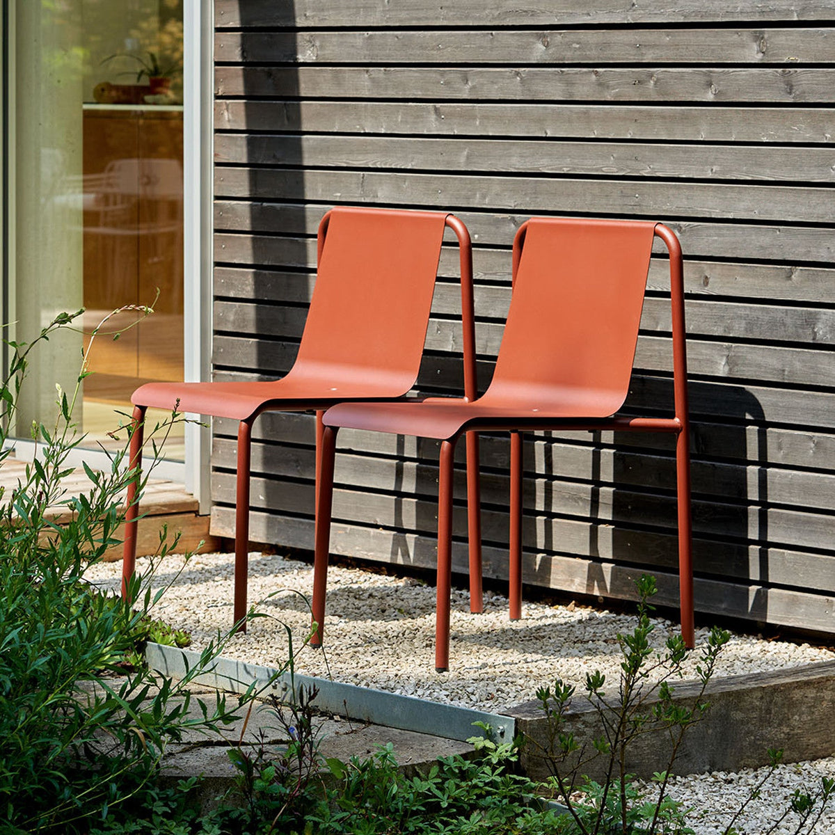 Two Tiptoe PANORAMA Outdoor Chairs against a timber wall, powder-coated steel