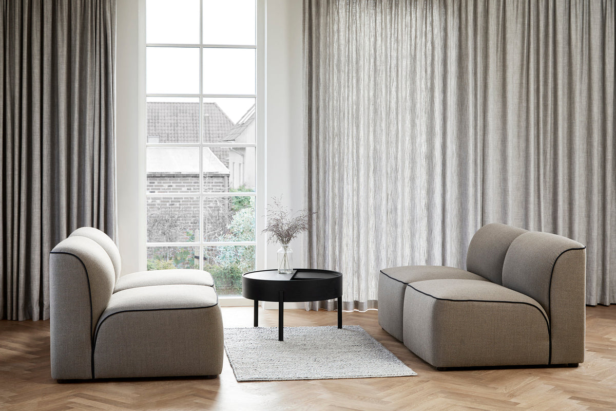 WOUD Arc Coffee Table in black painted ash, styled between two modular sofas in a living room