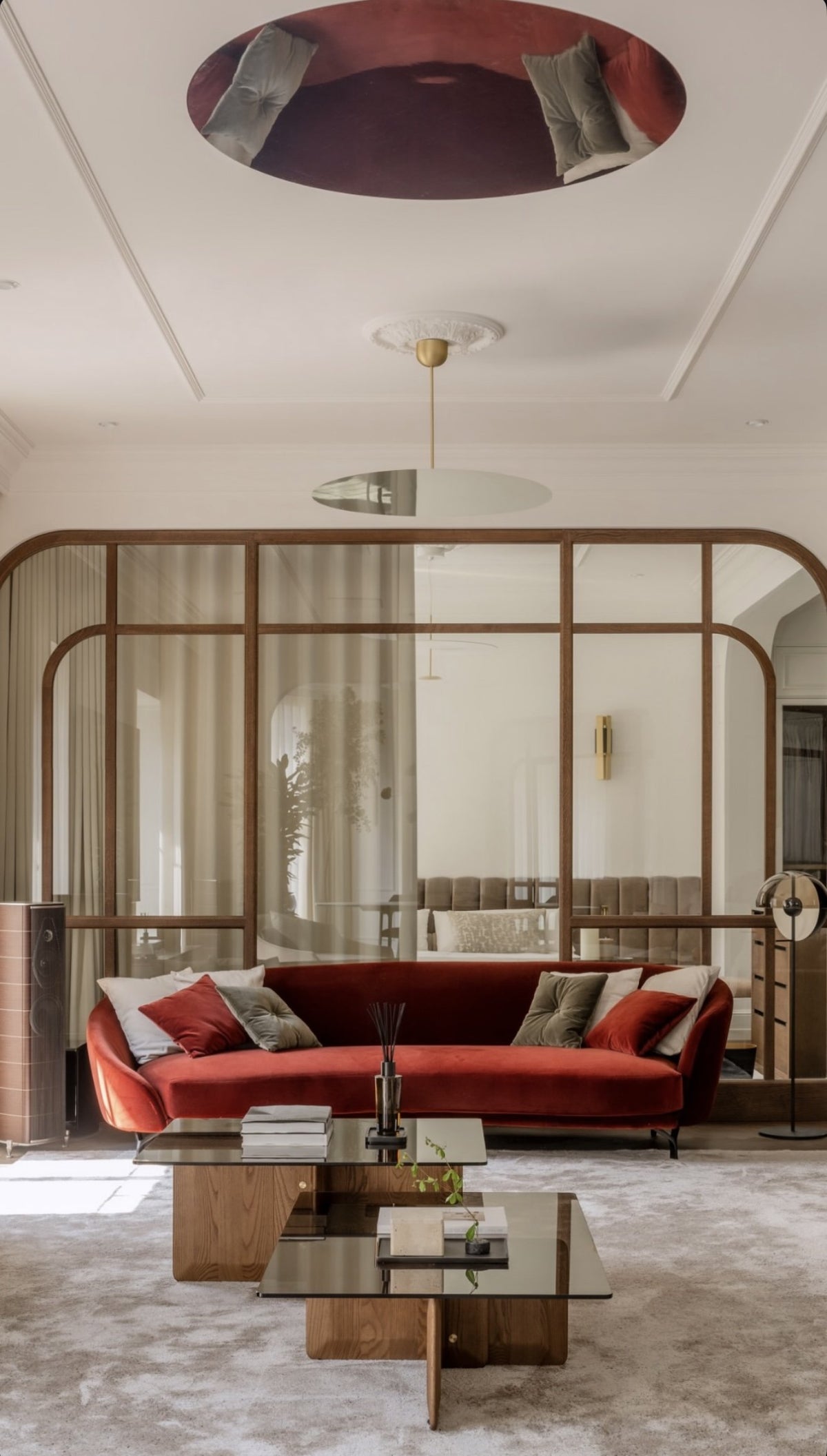 Luceplan Millimetro Pendant with a mirror disc above a red sofa, styled in an interior setting