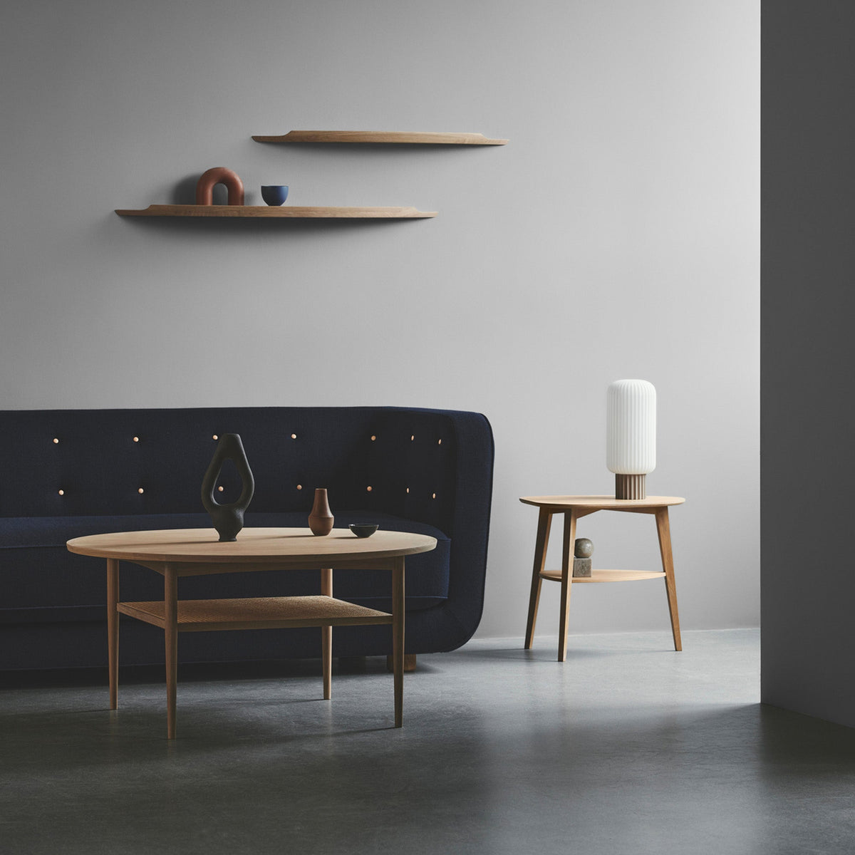 Two Aakjaer Arcus shelves above a sofa and an oak coffee table in a gray living room