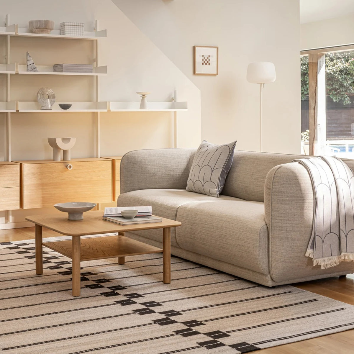 Case Oar rug with dark woven stripes under an oak coffee table in a living room