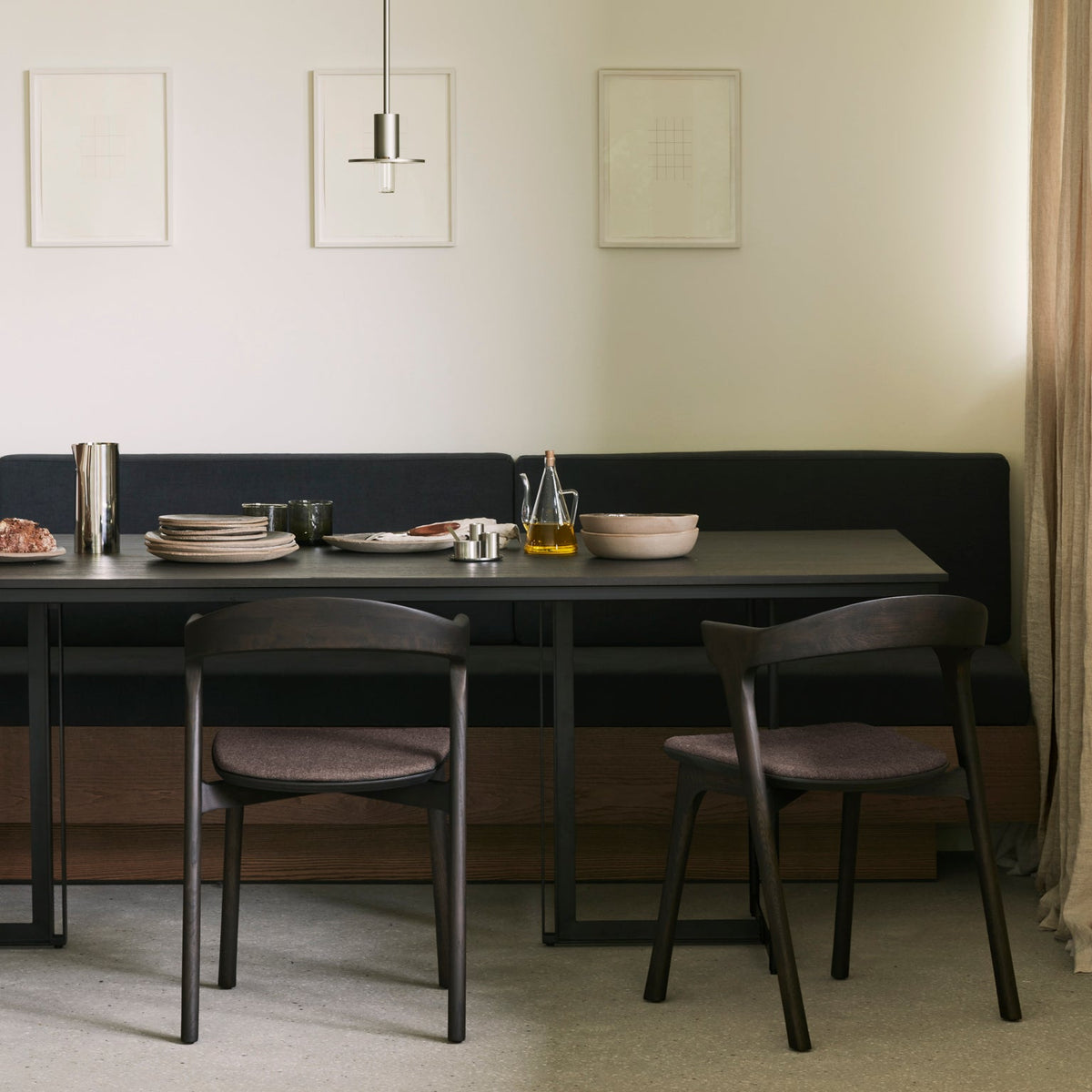 Ethnicraft Tacet Dining Table in dark brown teak with a banquette and dining chairs, styled in an interior setting