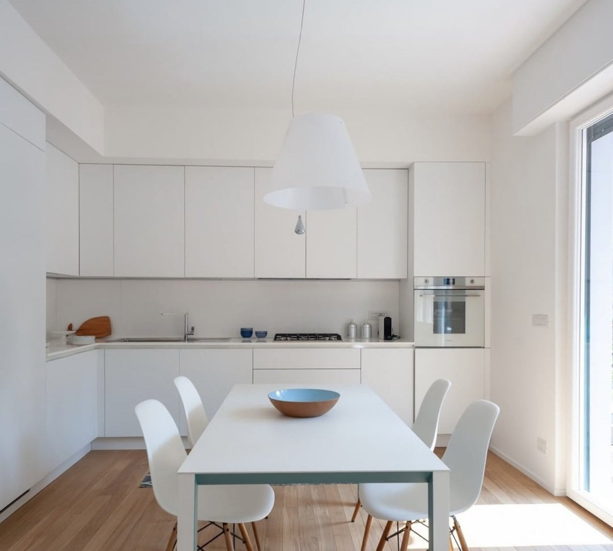 Luceplan Costanza Pendant with a white shade over a white dining table