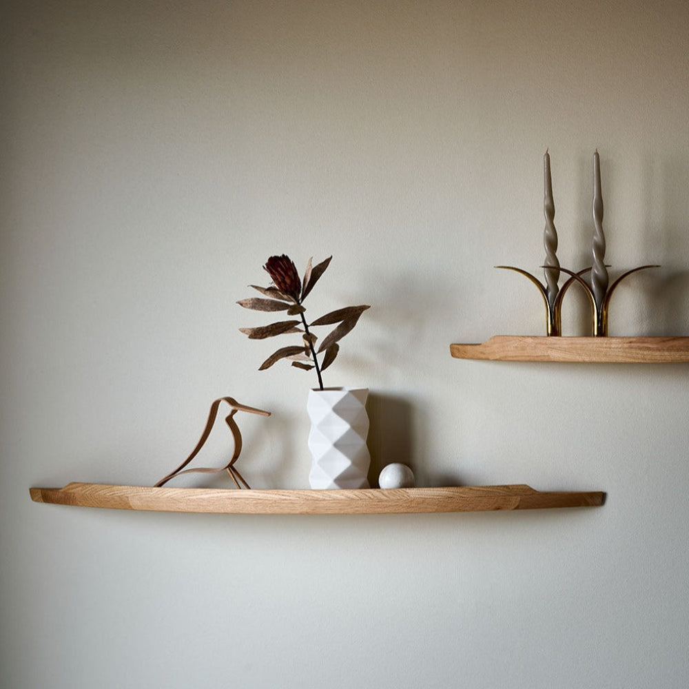 Two Aakjaer Arcus shelves in oak styled with a geometric vase, a bird figure and candlesticks