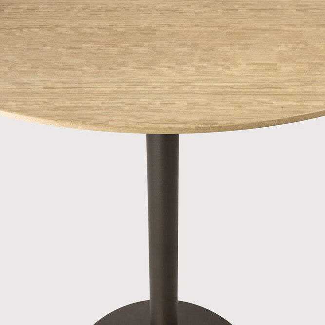 Detail of Ethnicraft Blend Bar Table showing the varnished solid oak top and Dark Bronze pedestal