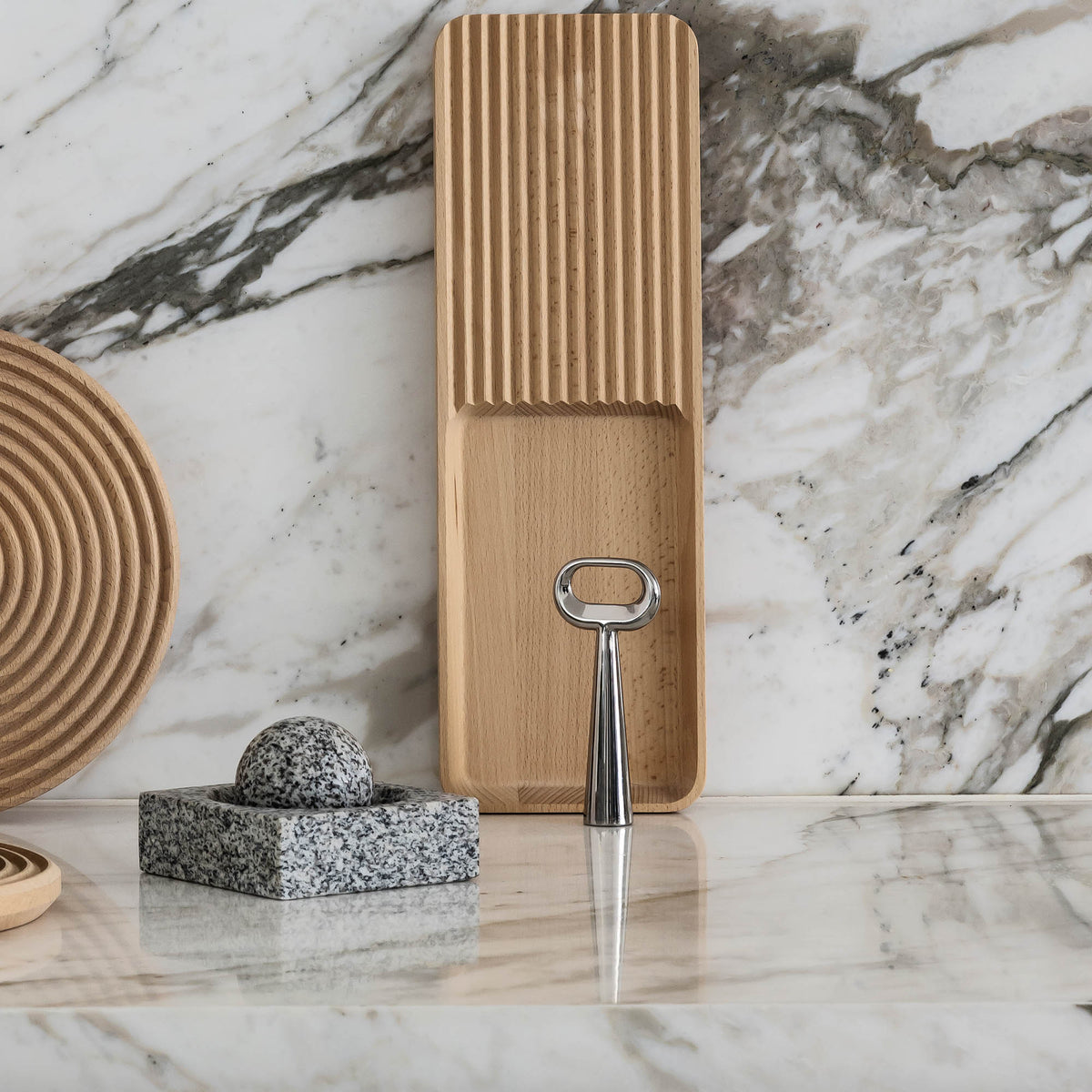 Case Stand Bottle Opener in polished stainless steel, styled on a marble counter with Case boards