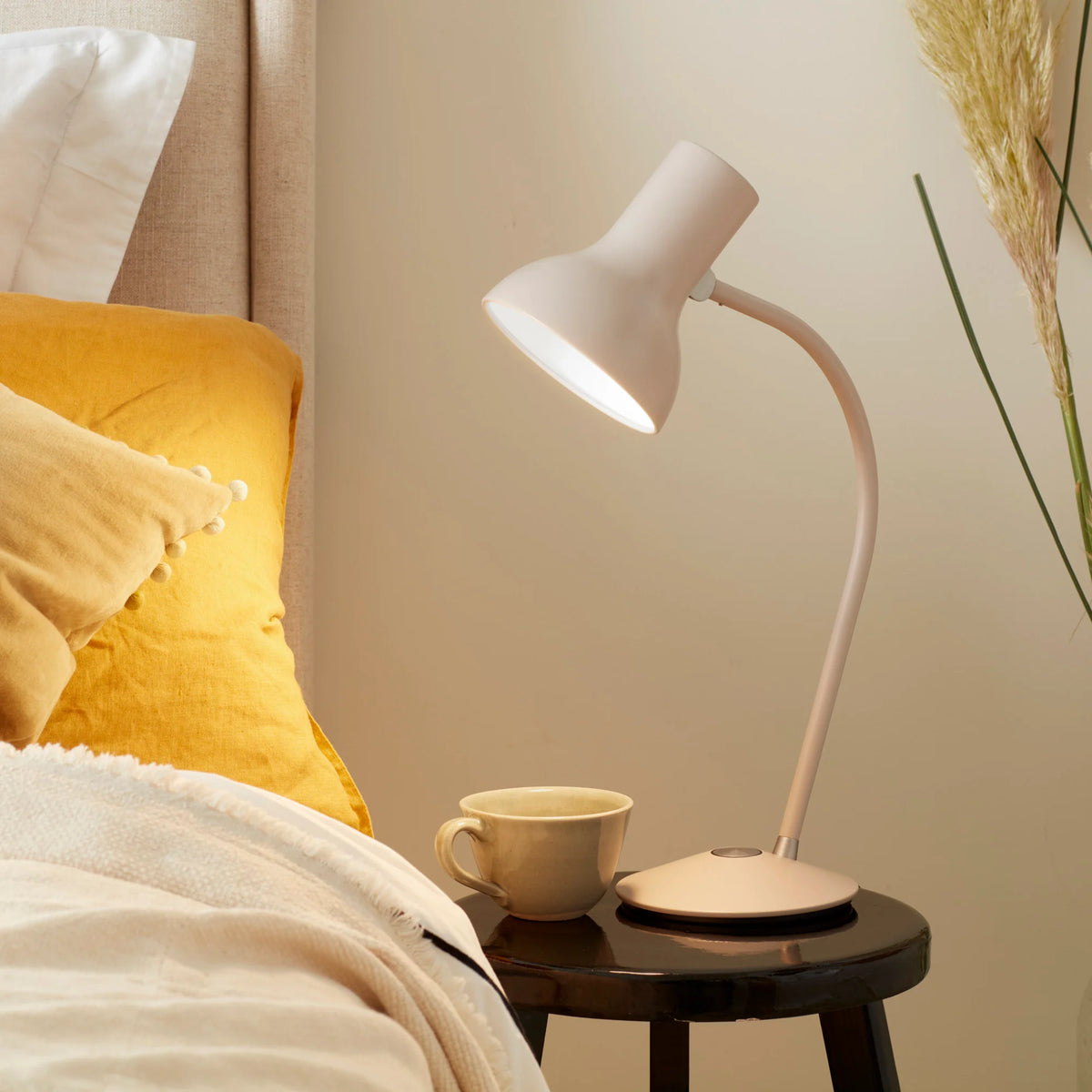 Anglepoise Type 75 Mini table lamp in Mole Gray on a bedside table with a yellow cushion