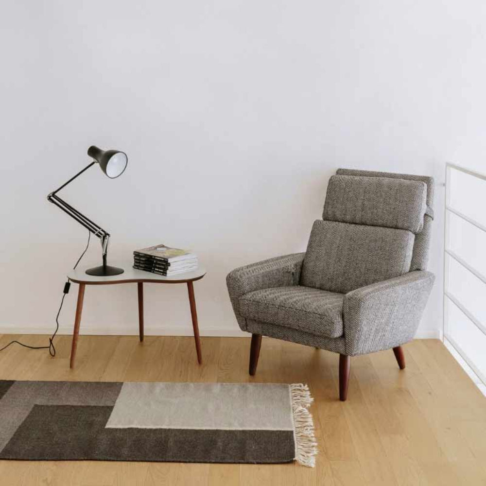 Anglepoise Type 75 desk lamp in black on a small side table next to a gray armchair