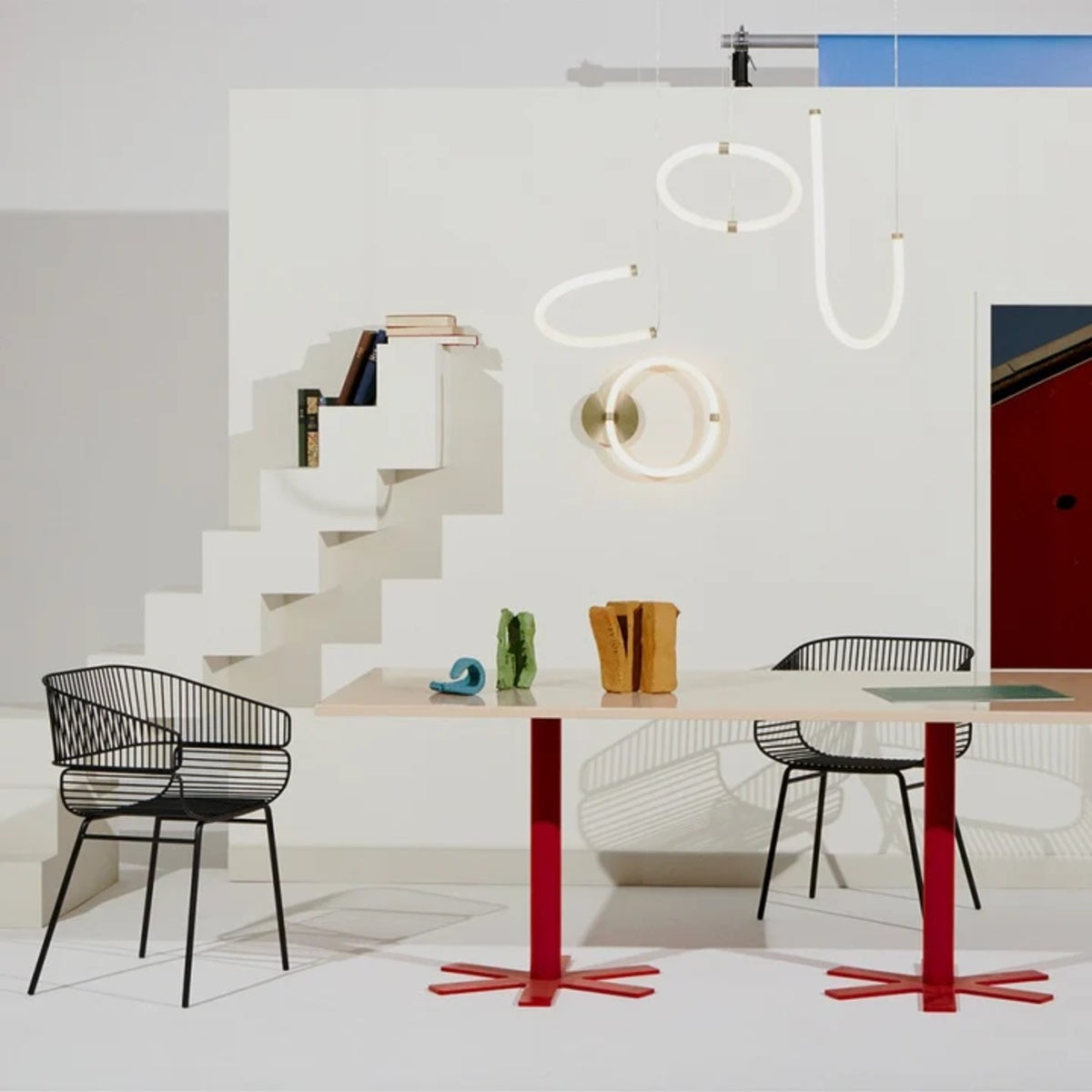Petite Friture Unseen J pendant light above a dining table with wire chairs