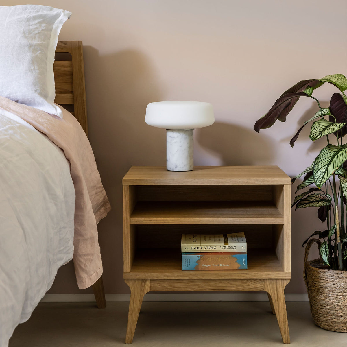 Case Valentine Bedside Table in Oak beside a bed with a lamp, styled in a bedroom, solid oak and oak veneer