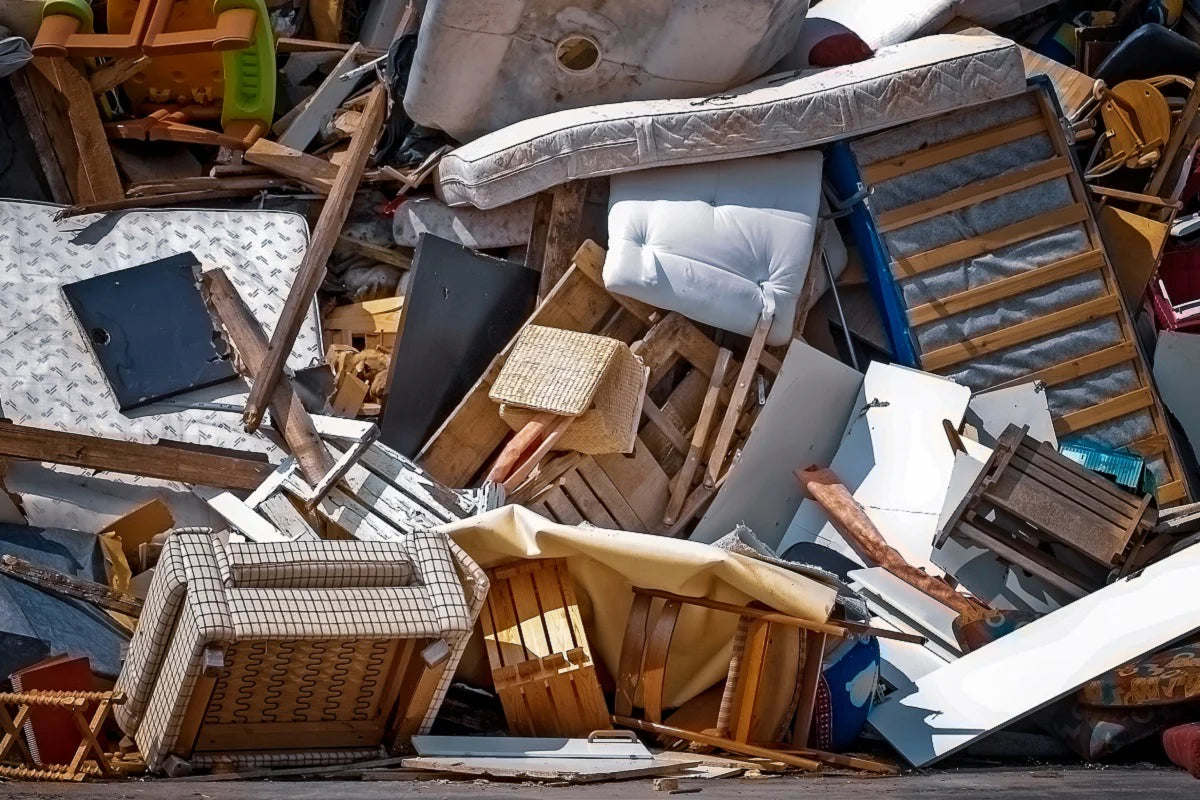 ile of discarded furniture, including broken chairs, mattresses, and wooden pieces, symbolizing the environmental impact of fast furniture and the importance of sustainable, eco-friendly alternatives promoted by Comosum.